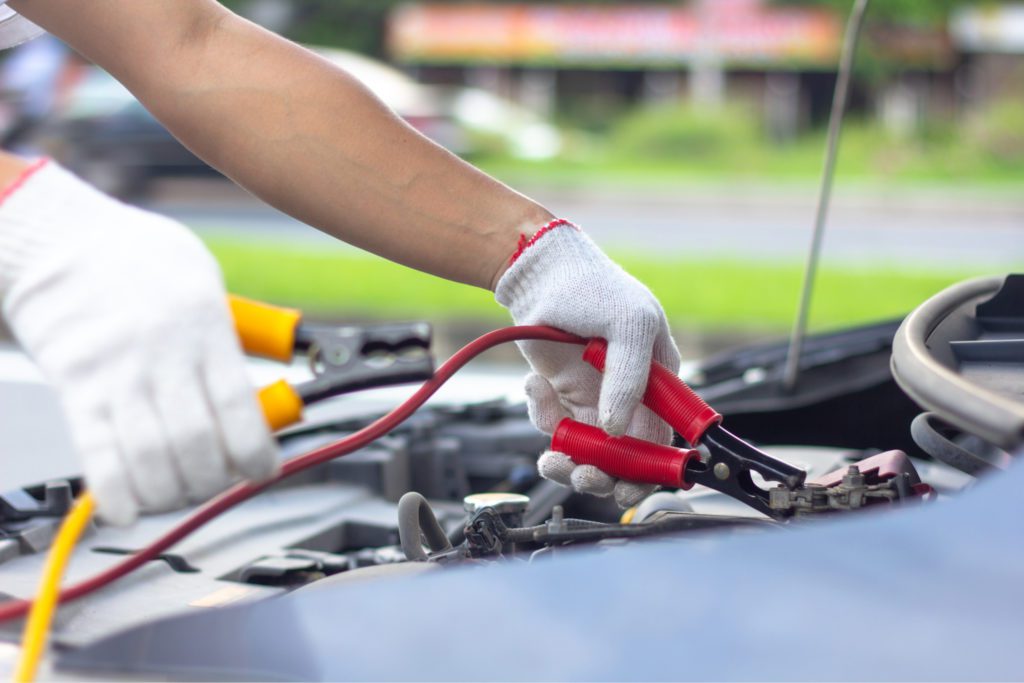 an electrical auto mechanic is testing a dead battery in a car