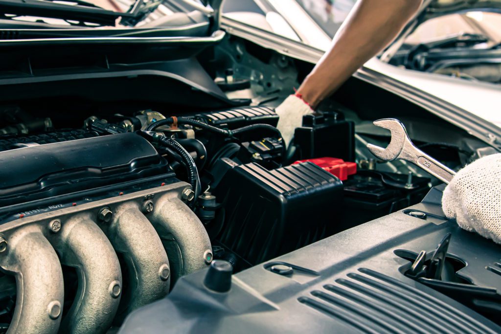 an electrical auto mechanic checks under the hood for electrical problems. 