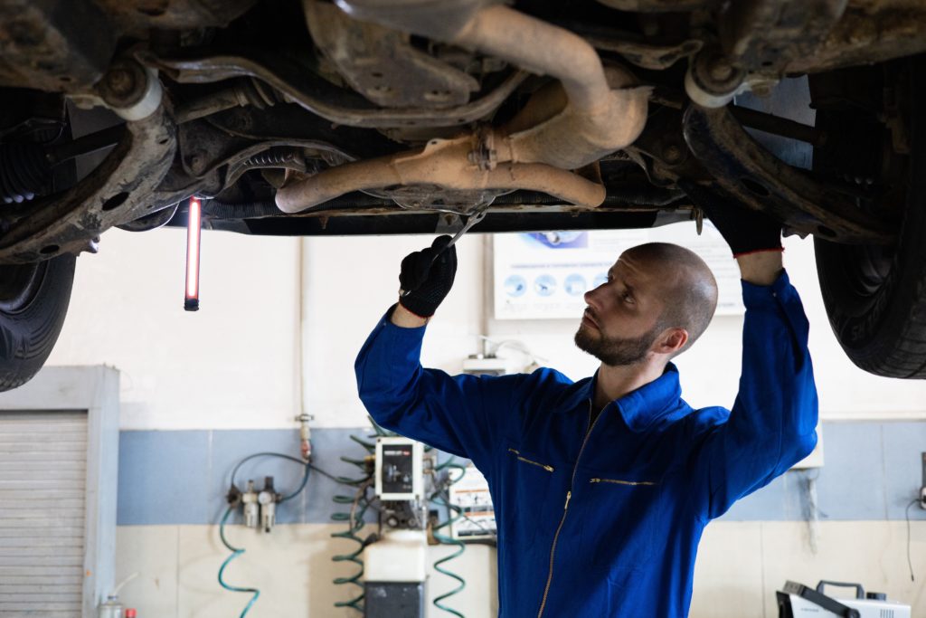A mechanic in Albuquerque checks a vehicle's exhaust system for needed repairs. 
