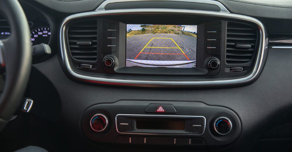 An mechanic in Albuquerque installs a backup camera in a vehicle showing the space behind a car to improve safety. 