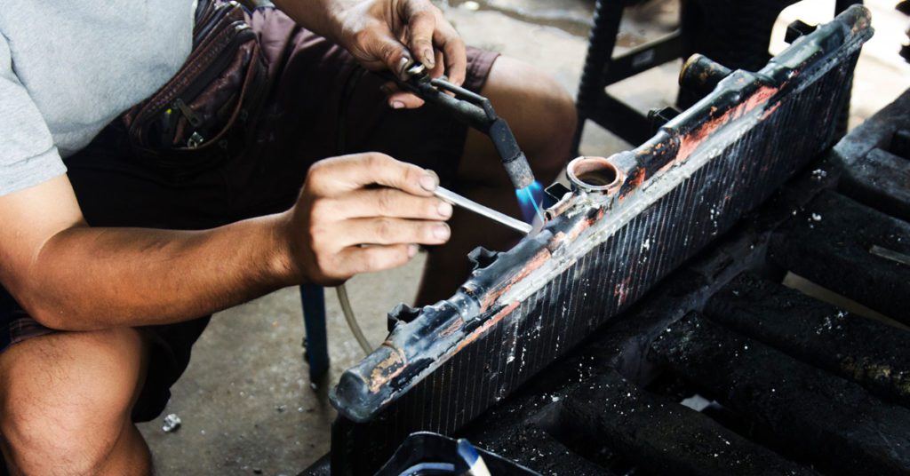 A radiator repair technician in Albuquerque welds a leak in an old radiator. 