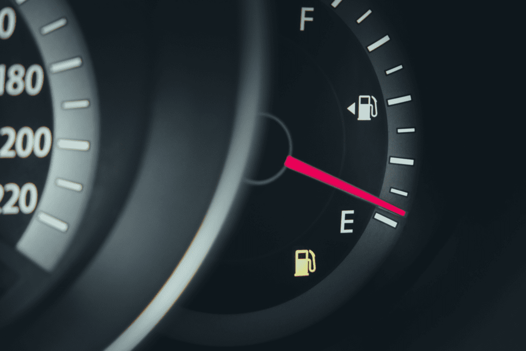 A low fuel light comes on in a vehicle dash which shows the fuel guage at nearly empty. 