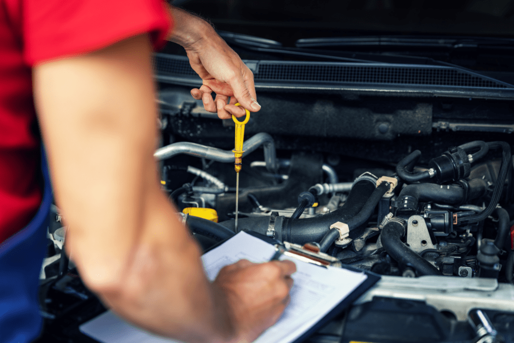 A mechanic skilled in engine repair in Albuquerque uses the dipstick to check the engine oil level in a vehicle. 
