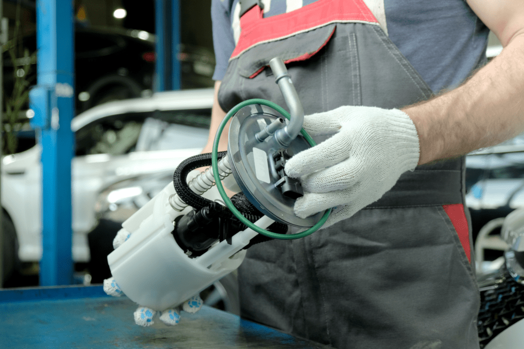 A mechanic holds a fuel pump for a vehicle in his hands. 
